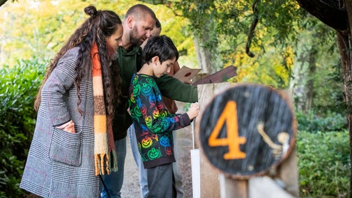 A family are solving clues and cracking codes, they are consulting their trail sheet next to station number 4.